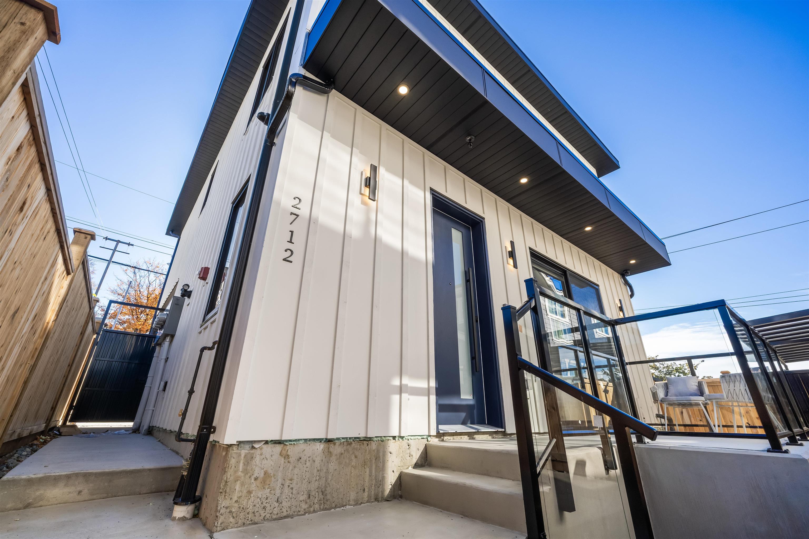 2712 Kitchener Street — the rear laneway house, white siding and dark blue door